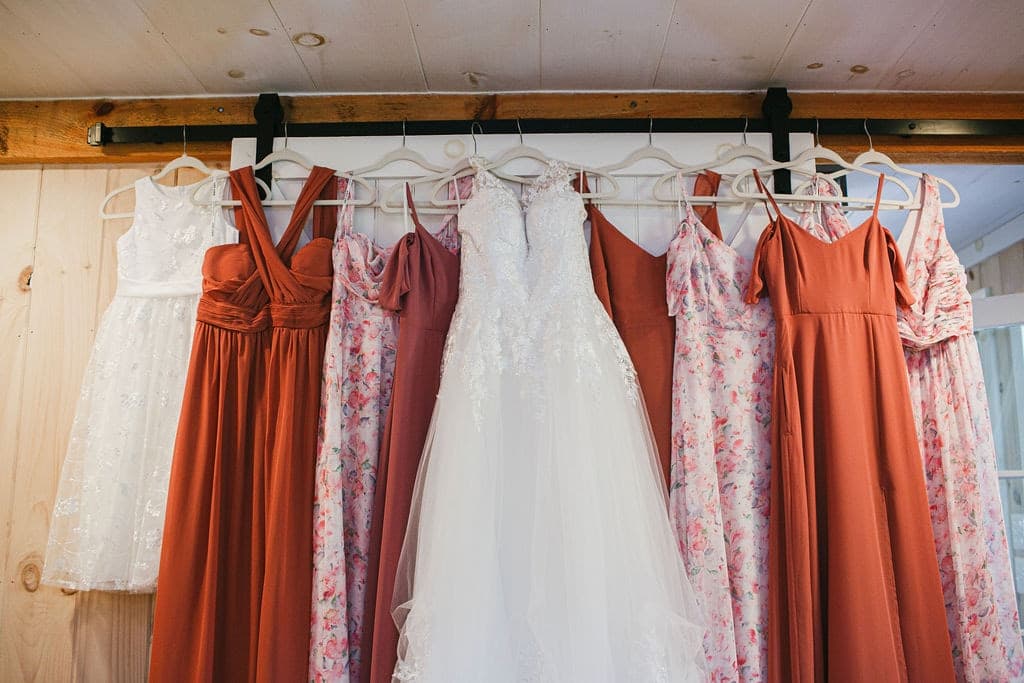 A collection of bridesmaid and bridal dresses hanging in a row.