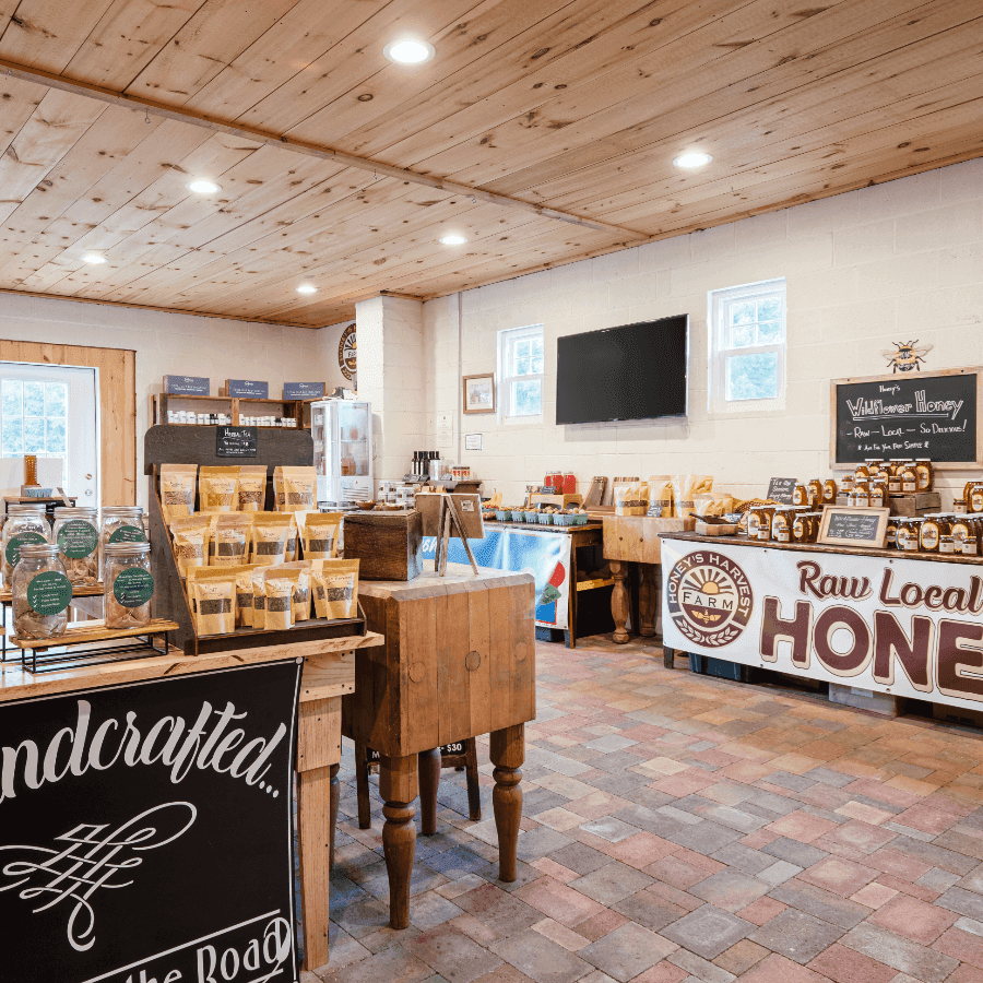 A cozy shop interior featuring various locally produced goods, including honey and packaged snacks, with wooden cabinetry and a warm ambiance.