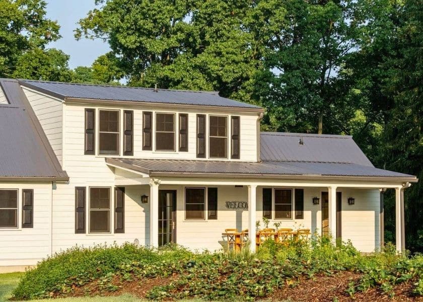 Farmhouse exterior with metal roof and covered porch seating at Honeys Farmhouse in Lothian, Maryland. Farmhouse exterior with metal roof and covered porch seating at Honeys Farmhouse in Lothian, Maryland.